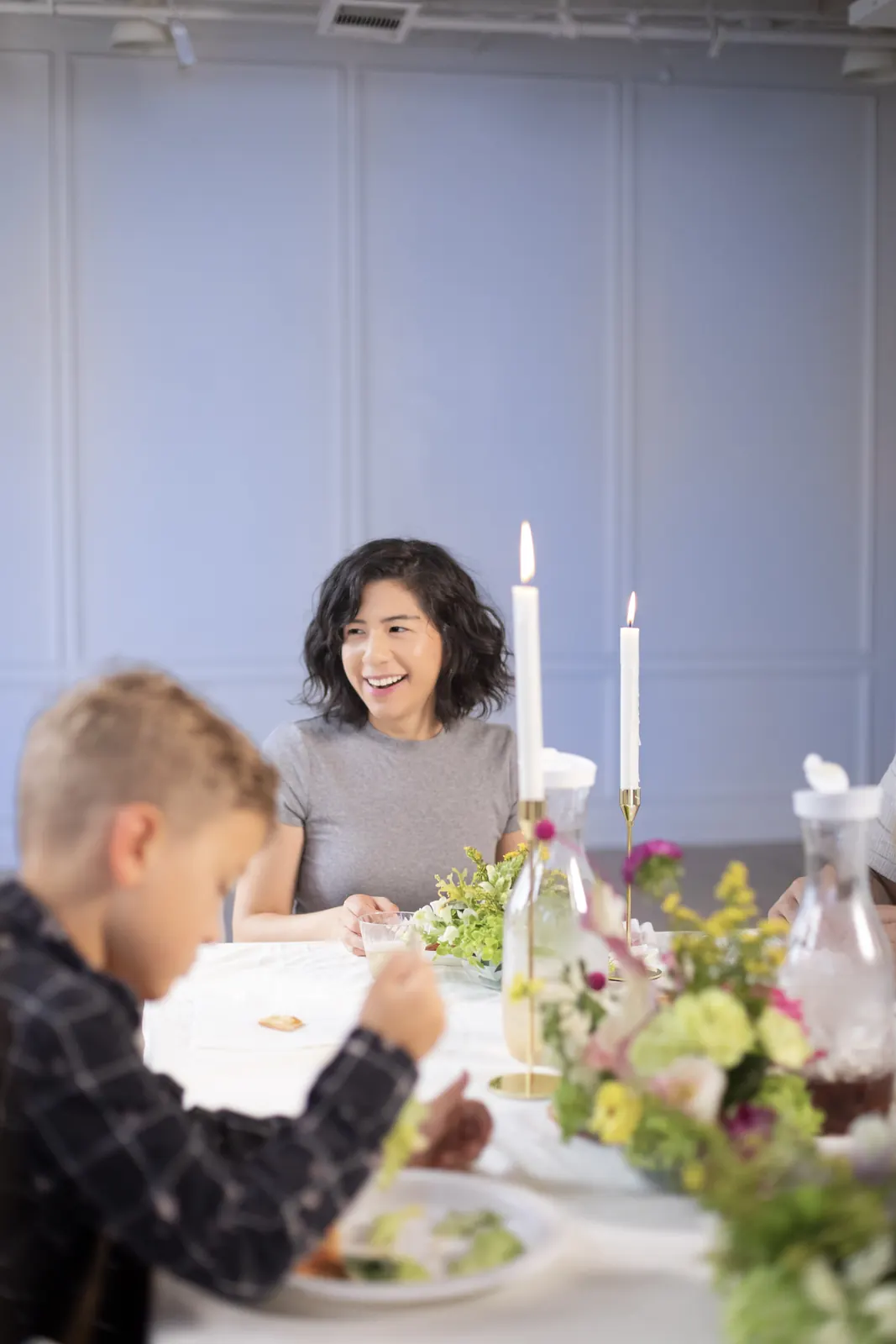 A woman laughing beside a child at a candlelit dinner table
