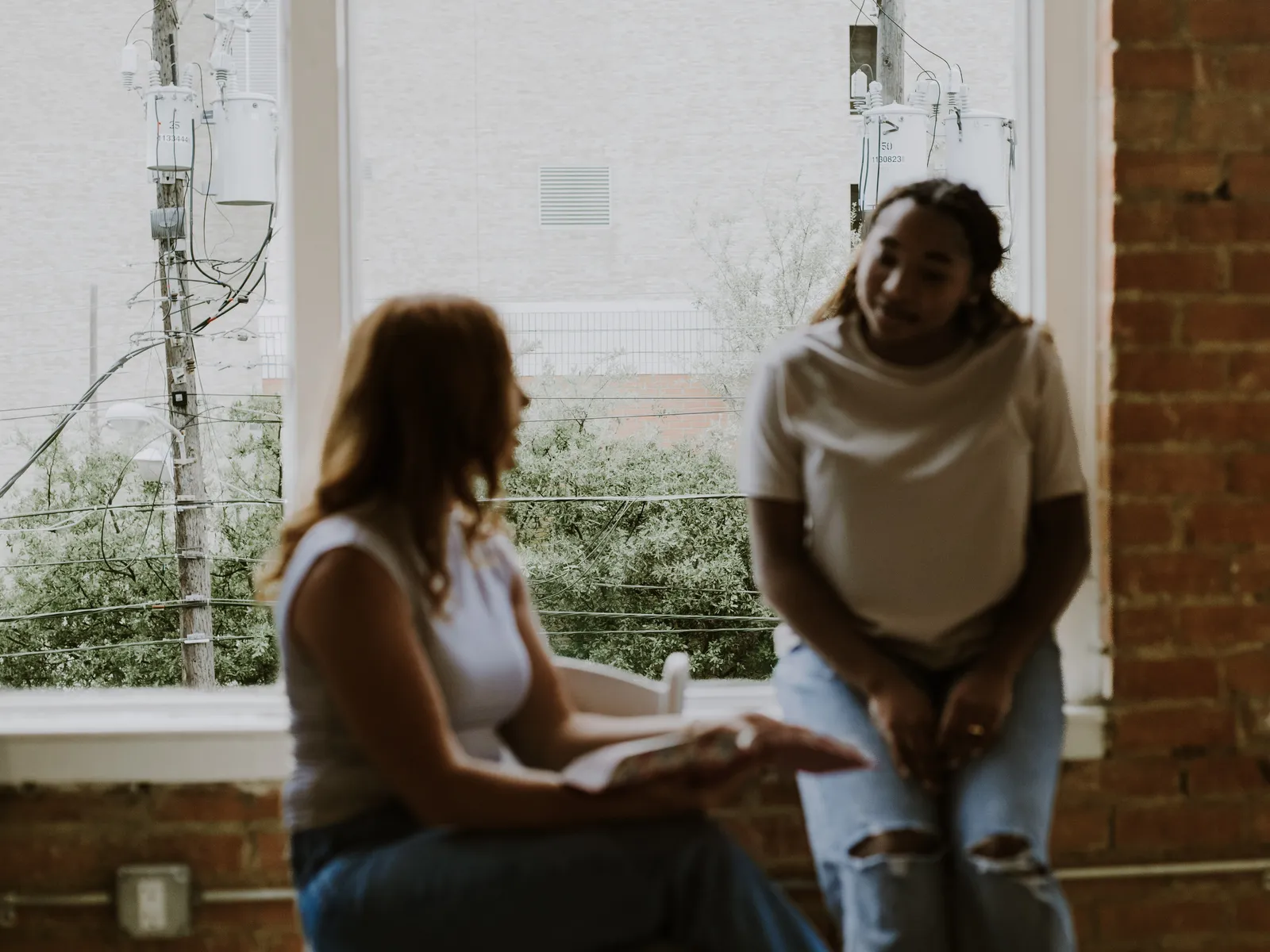 Two women with an open Bible by the window