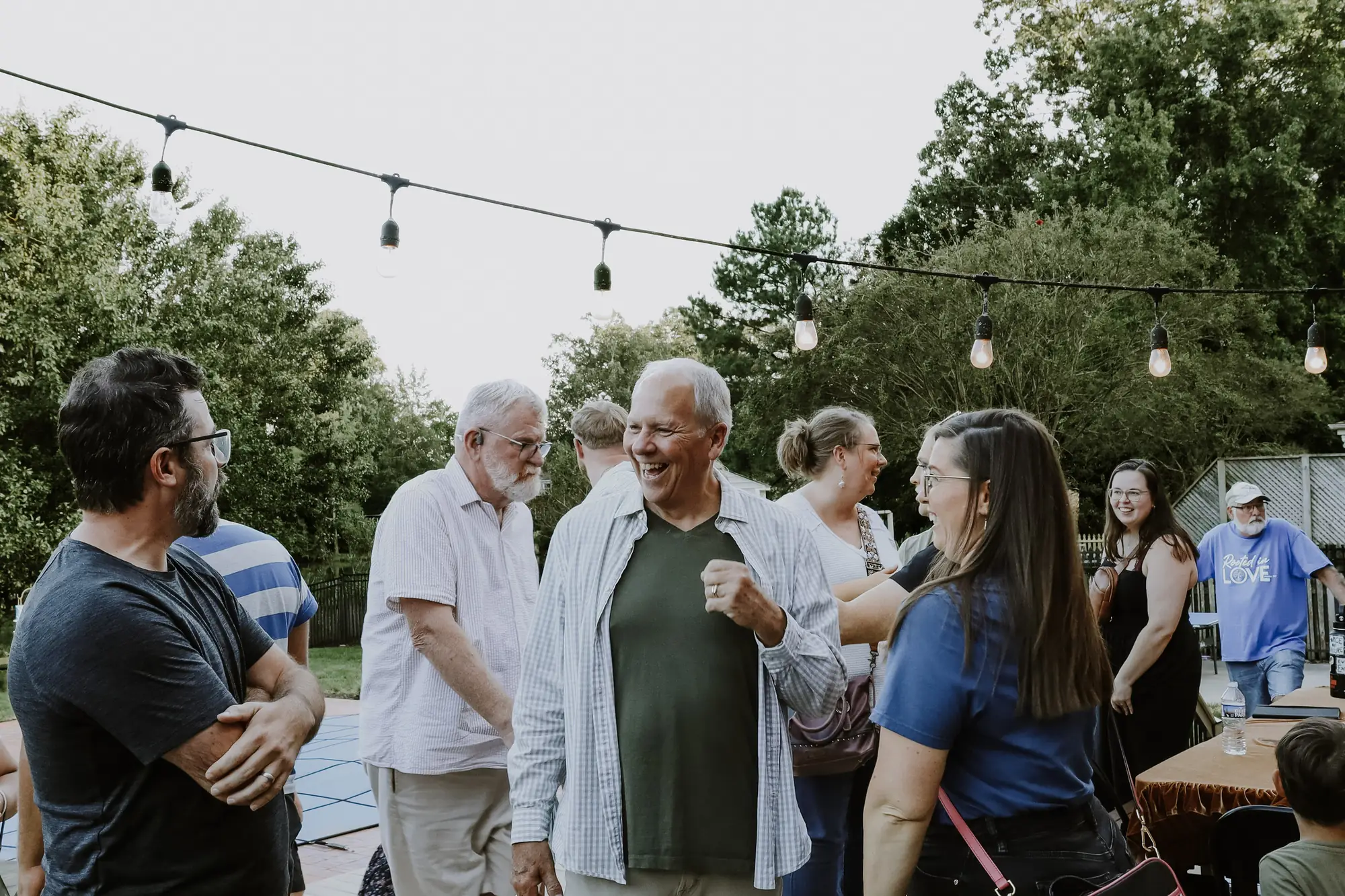 Friends talking and laughing outdoors under string lights